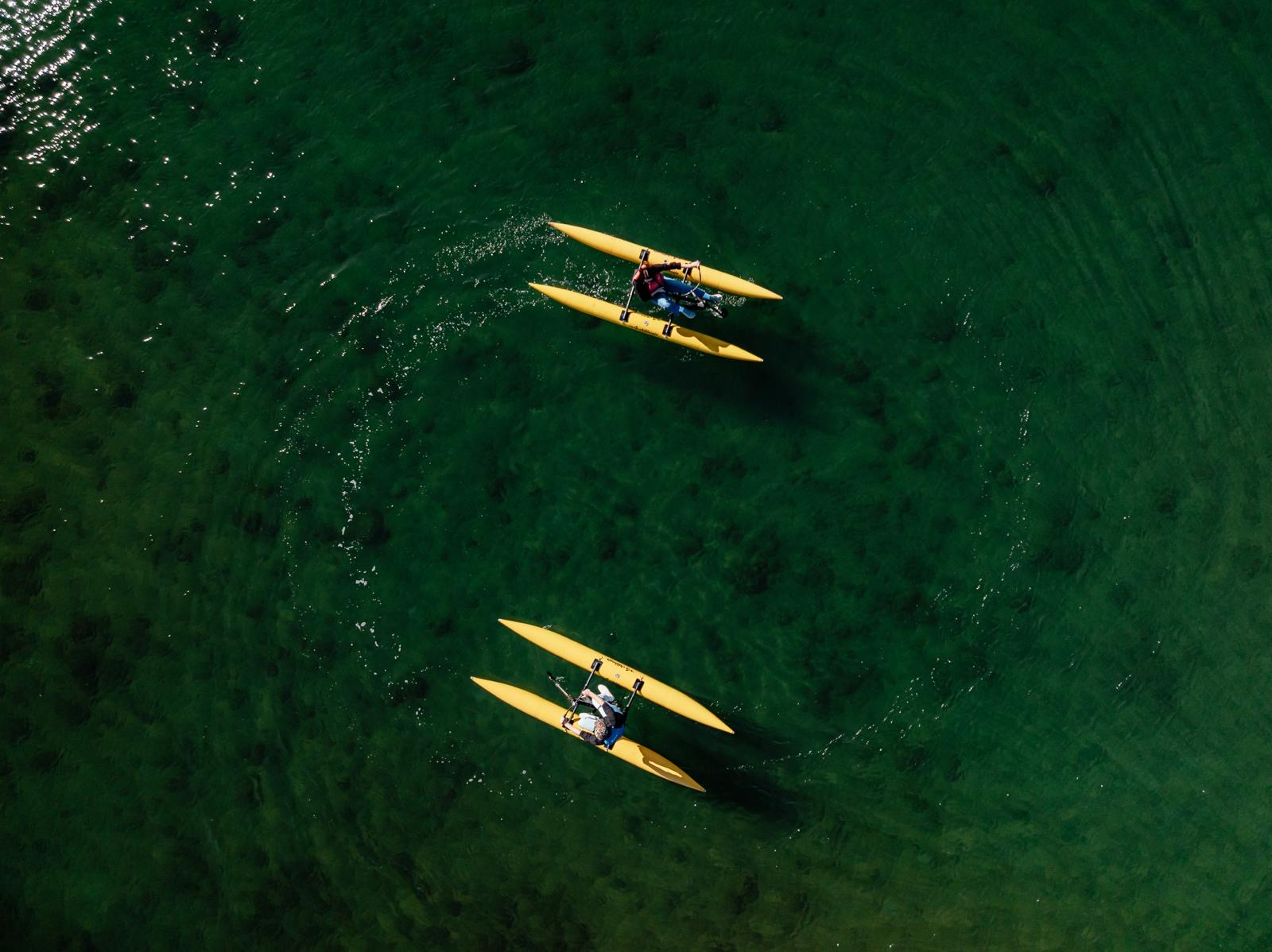 Aerial view of two yellow ChiliBoats waterbikes on clear green water